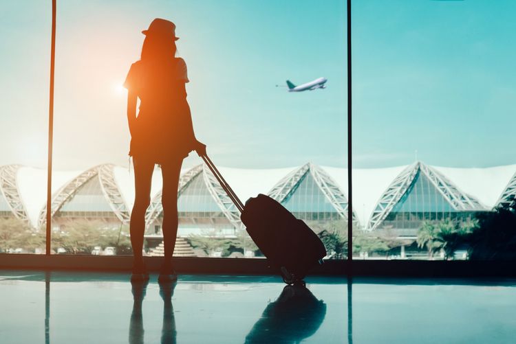Silhouette of woman at airport with carry-on suitcase