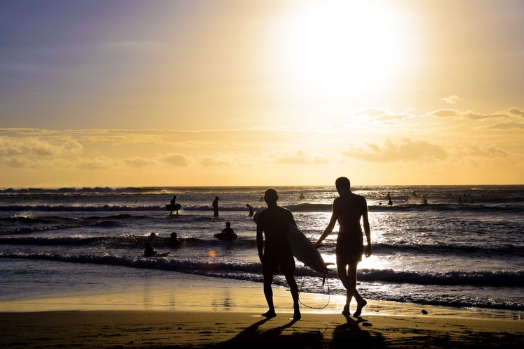 Surfeurs sur la plage de Saint-Leu au moment du coucher du soleil