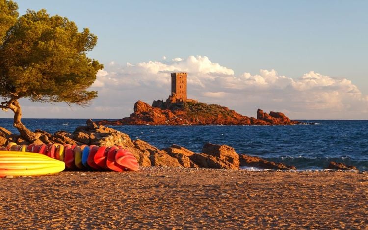 Coucher de soleil sur la plage rocheuse avec vue sur l’île d’Or, île dorée avec tour carrée médiévale près du cap Dramont, Saint-Raphaël, Côte d’Azur