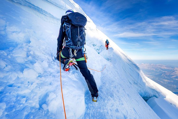 Un alpiniste en train train de gravir un sommet