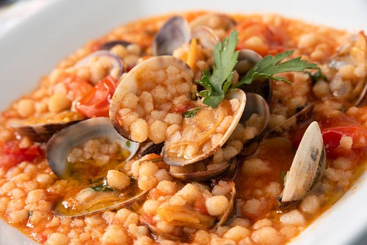 Fregula, pâtes sardes traditionnelles avec des tomates et des palourdes,