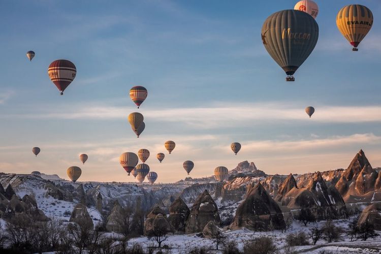 Mongolfiere sorvolano il paesaggio montuoso in inverno all'alba in Cappadocia, Parco Nazionale di Goreme, Turchia.