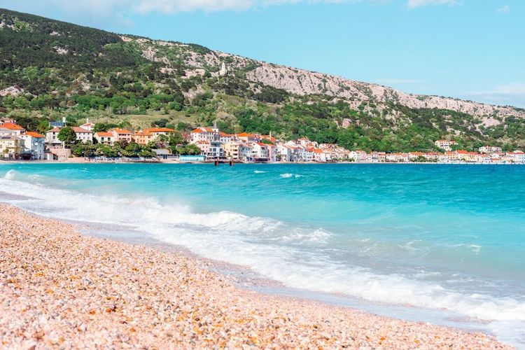 Ville côtière avec des maisons colorées près de plage de galets et mer turquoise